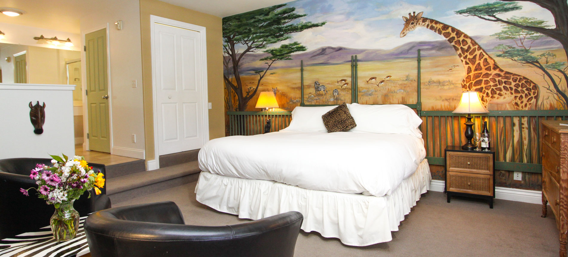 safari room with bed, fireplace, chairs and artwork