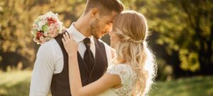 sunset view of bride and groom hugging with bouquet on groom’s shoulder